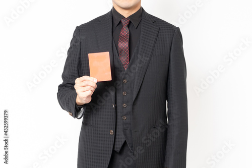 白背景の前に立って、レッドカードを示す男性ビジネスマン