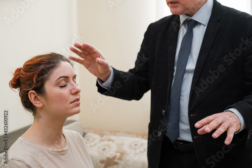 Mature gray-haired man hypnotizes Caucasian woman during hypnotherapy session. The psychologist uses alternative treatments for the subconscious mind
