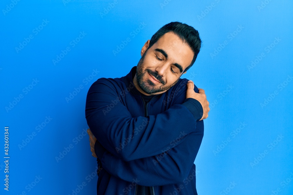 Young hispanic man wearing casual clothes hugging oneself happy and positive, smiling confident. self love and self care Young hispanic man wearing casual clothes hugging oneself happy and positive, smiling confident. self love and self care