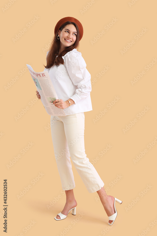 Fototapeta premium Young woman with newspaper on color background