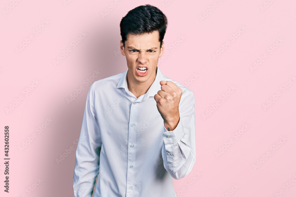 Young hispanic business man wearing business clothes angry and mad raising fist frustrated and furious while shouting with anger. rage and aggressive concept. Young hispanic business man wearing business clothes angry and mad raising fist frustrated and furious while shouting with anger. rage and aggressive concept.