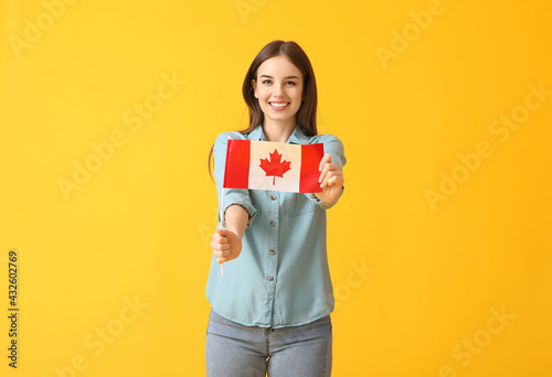 Beautiful young woman with the flag of Canada on color background
