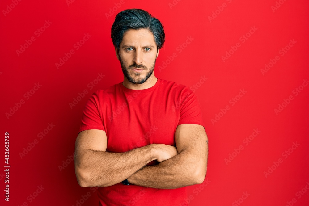 Young hispanic man wearing casual red t shirt skeptic and nervous, disapproving expression on face with crossed arms. negative person. Young hispanic man wearing casual red t shirt skeptic and nervous, disapproving expression on face with crossed arms. negative person.