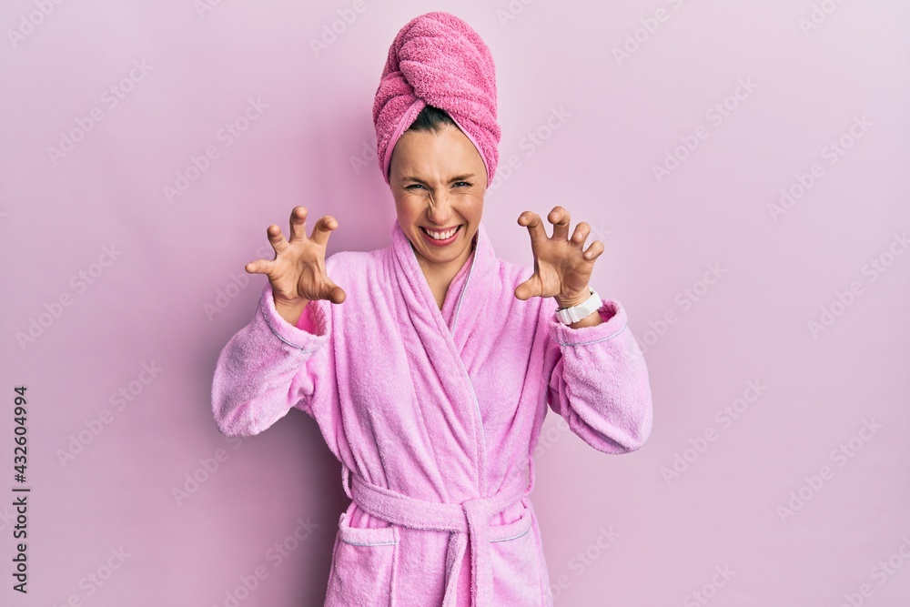 Young blonde woman wearing shower towel cap and bathrobe smiling funny doing claw gesture as cat, aggressive and sexy expression Young blonde woman wearing shower towel cap and bathrobe smiling funny doing claw gesture as cat, aggressive and sexy expression