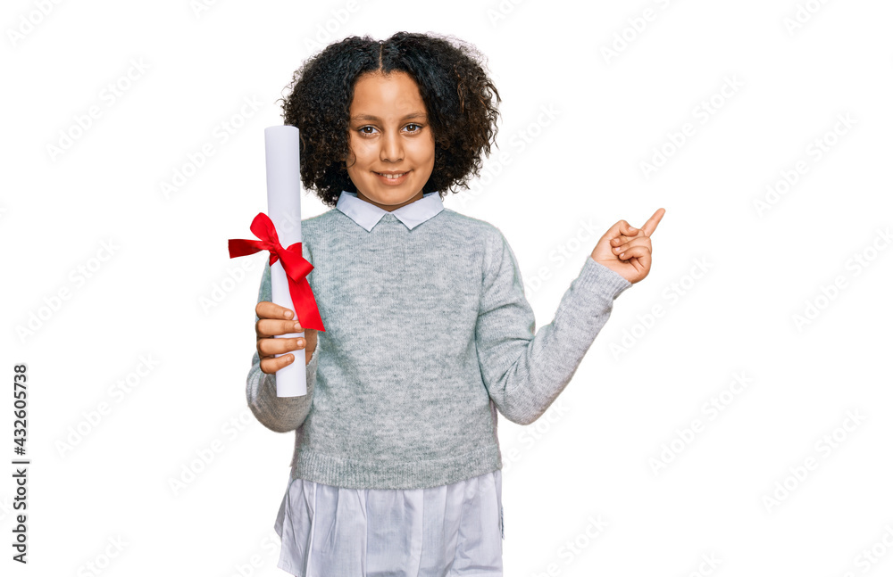 Young little girl with afro hair holding graduate degree diploma smiling happy pointing with hand and finger to the side Young little girl with afro hair holding graduate degree diploma smiling happy pointing with hand and finger to the side