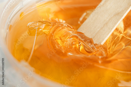 Sugar paste or wax honey in a transparent jar on a white background. Sugaring. Depilation and beauty concept. Waxing.