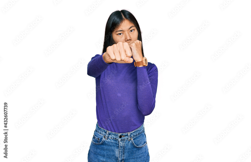 Beautiful young asian woman wearing casual clothes punching fist to fight, aggressive and angry attack, threat and violence Beautiful young asian woman wearing casual clothes punching fist to fight, aggressive and angry attack, threat and violence