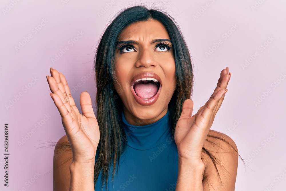 Young latin transsexual transgender woman with hands over face angry and mad screaming frustrated and furious, shouting with anger looking up. Young latin transsexual transgender woman with hands over face angry and mad screaming frustrated and furious, shouting with anger looking up.