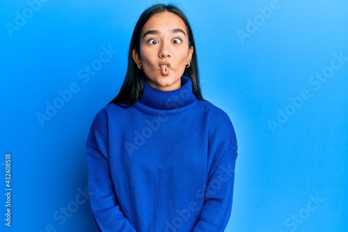 Young asian woman wearing casual winter sweater making fish face with lips, crazy and comical gesture. funny expression. © Krakenimages.com