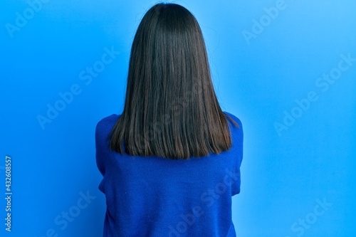 Obraz na plátně Young asian woman wearing casual winter sweater standing backwards looking away