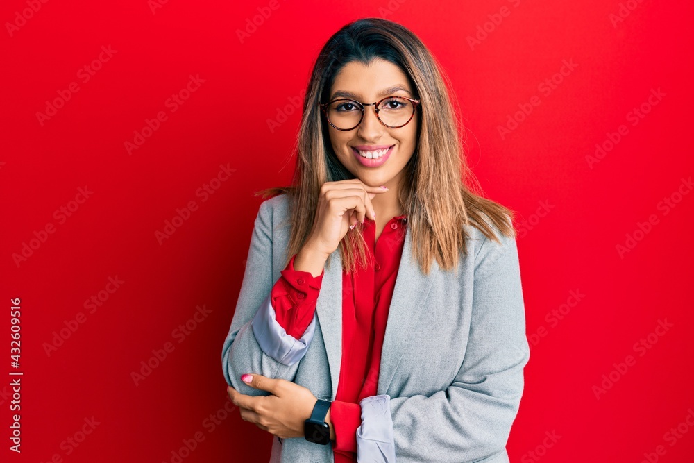 Beautiful brunette woman wearing business shirt and glasses smiling looking confident at the camera with crossed arms and hand on chin. thinking positive. Beautiful brunette woman wearing business shirt and glasses smiling looking confident at the camera with crossed arms and hand on chin. thinking positive.