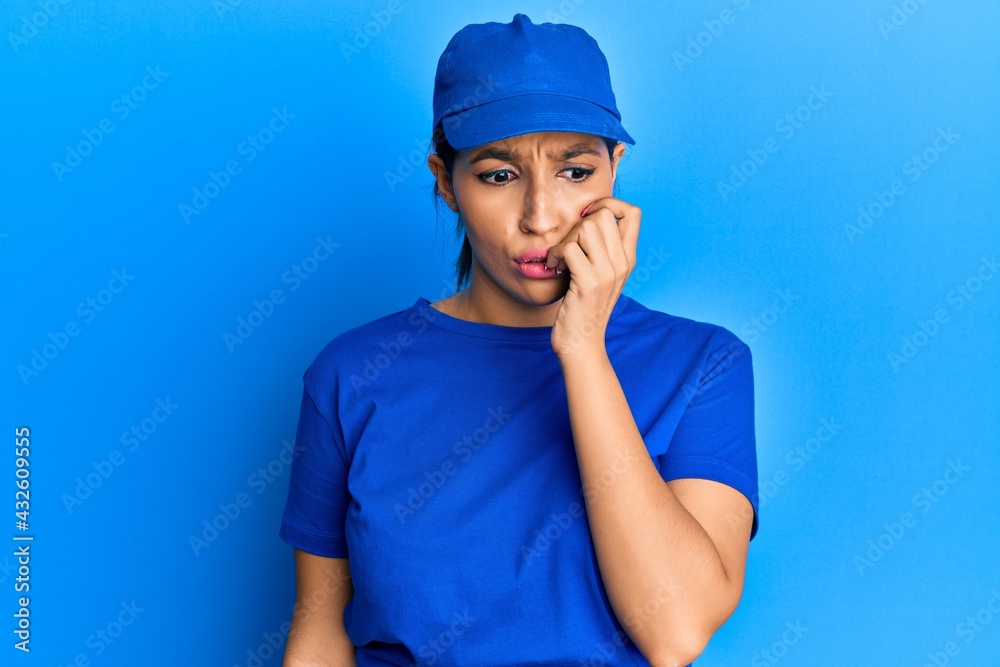 Beautiful brunette woman wearing delivery uniform looking stressed and nervous with hands on mouth biting nails. anxiety problem. Beautiful brunette woman wearing delivery uniform looking stressed and nervous with hands on mouth biting nails. anxiety problem.
