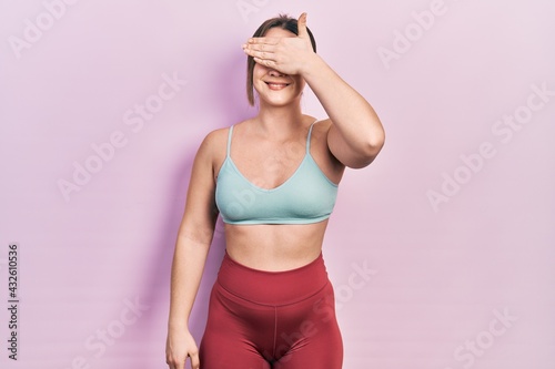 Young hispanic girl wearing sportswear smiling and laughing with hand on face covering eyes for surprise. blind concept.