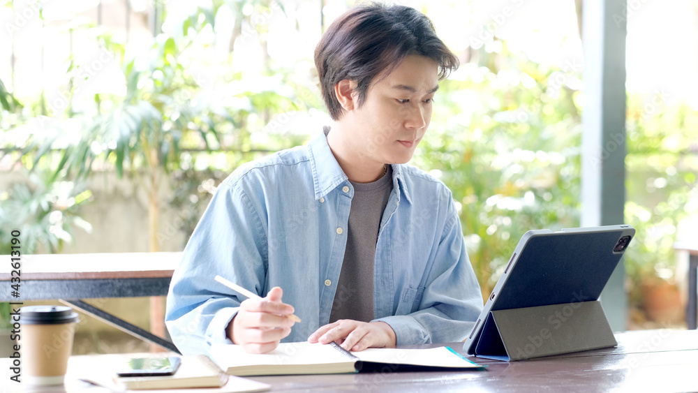 Online studying class, Student man hand writing on notebook while using digital tablet for e learning, Adult male university, college student study online course at home, education, Work from home Online studying class, Student man hand writing on notebook while using digital tablet for e learning, Adult male university, college student study online course at home, education, Work from home