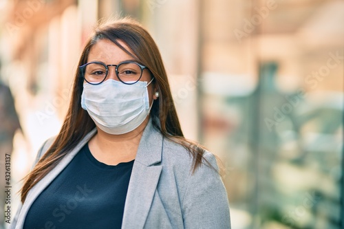 Young hispanic plus size businesswoman wearing medical mask standing at the city.