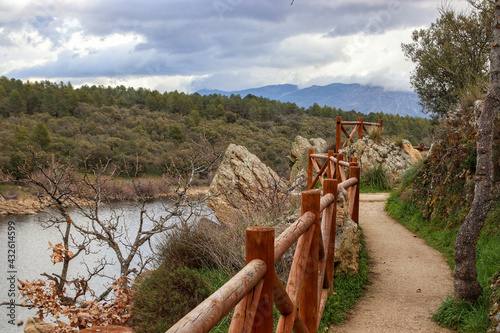 Narrow footpath with a wooden fence along the river photo