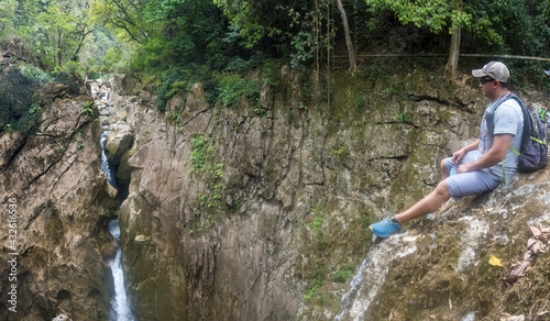 Closeup shot of a Hispanic hiker sitting on top of the Popocatl waterfall photo