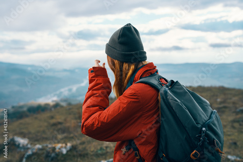 energetic woman in warm clothes with backpack travel tourism mountains landscape back view