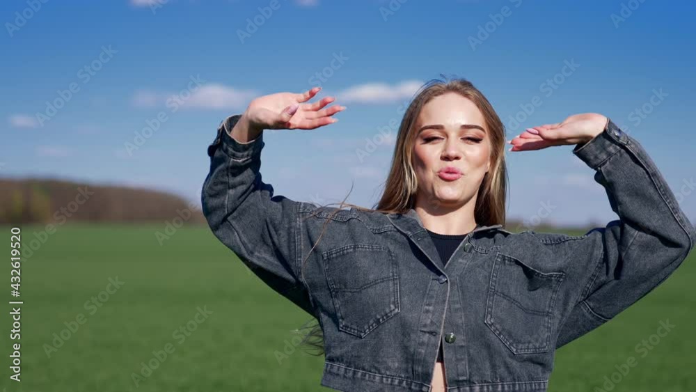 Portrait of a cheerful girl. Beautiful young woman in jeans jacket jumping and looking on camera on blur nature landscape in spring.