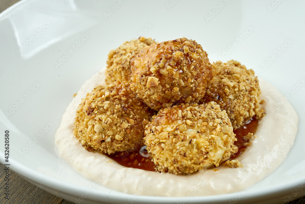 A traditional dish of Ukrainian cuisine is Gombovtsy or Baoji. Sweet balls of semolina and plum jam with white sauce. served in a white plate on a wooden background A traditional dish of Ukrainian cuisine is Gombovtsy or Baoji. Sweet balls of semolina and plum jam with white sauce. served in a white plate on a wooden background