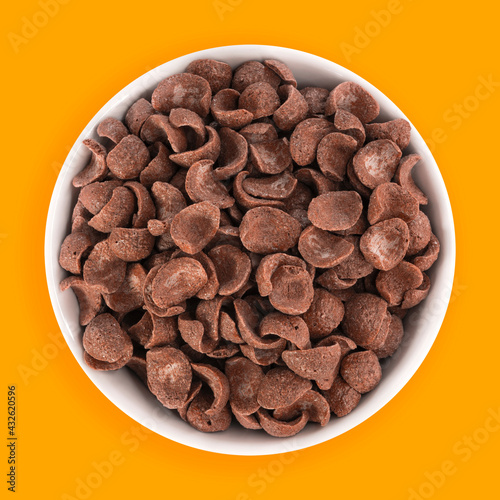 Foto Top view of bowl with sweet chocolate cereal flakes for breakfast on yellow back