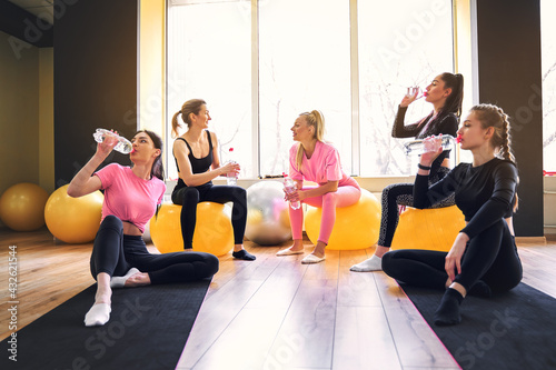 Group of athletic women having fun on a break during sports training, drink fresh water