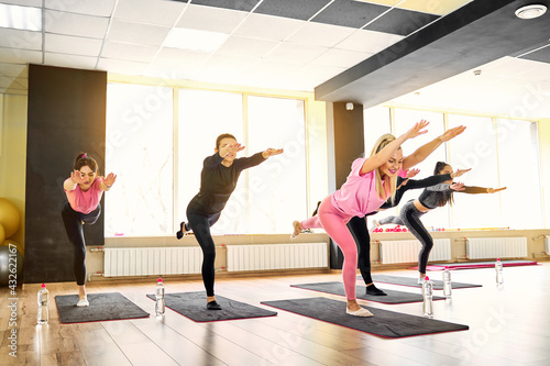 Group of young sporty attractive people practicing yoga lesson with instructor