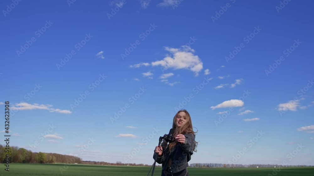 Beautiful young singer dancing with a microphone on a field. Pretty female soloist singing and jumping cheerfully outdoors. Slow motion. Beautiful young singer dancing with a microphone on a field. Pretty female soloist singing and jumping cheerfully outdoors. Slow motion.