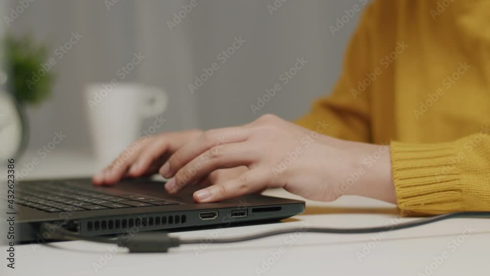 Close-up of hands typing keyboard and scrolling touchpad on a laptop and research through the internet online at home. Close-up of hands typing keyboard and scrolling touchpad on a laptop and research through the internet online at home.