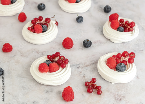 Meringues or mini Pavlova. Sweet dessert decorated with different berries. Fresh baking concept. Selective focus.