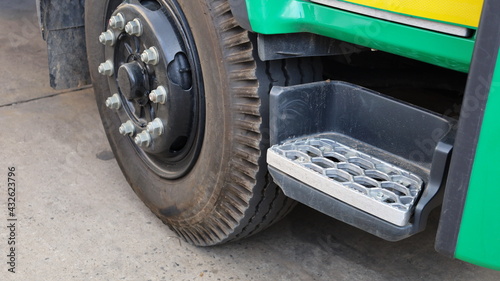 Metal staircase on truck. Aluminum ladder on the front wheel for climbing up the green truck sedan on a cement background. Close focus on the subject