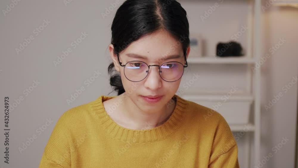 Beautiful young Asian female sitting in home office and research through the internet online on the computer laptop at home. Beautiful young Asian female sitting in home office and research through the internet online on the computer laptop at home.