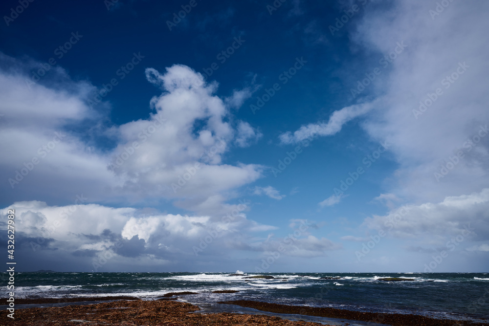 sunny day on the coast with storm clouds on the horizon sunny day on the coast with storm clouds on the horizon