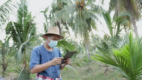 Thai gardeners wear a mask to protect against the virus covid-19 Intentionally reading news on the tablet screen in the garden, the concept of follow-up on coronavirus-19 and the economy