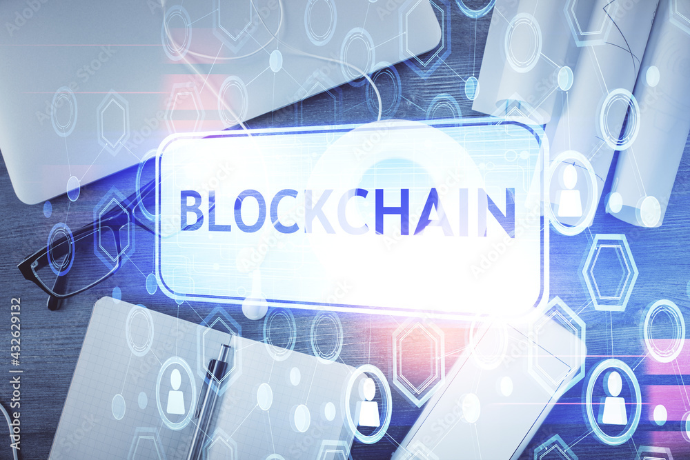Blockchain theme hologram drawings over computer on the desktop background. Top view. Multi exposure. Concept of cryptoeconomy. Blockchain theme hologram drawings over computer on the desktop background. Top view. Multi exposure. Concept of cryptoeconomy.