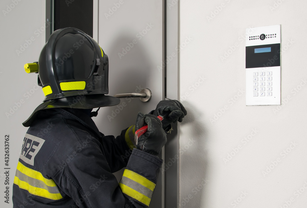 Fototapeta premium firefighter in protective uniform and helmet opens the closed door