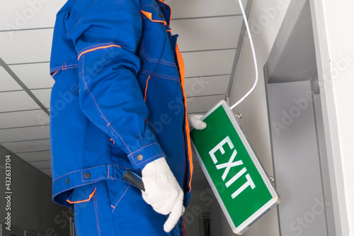 worker places an emergency exit sign photo