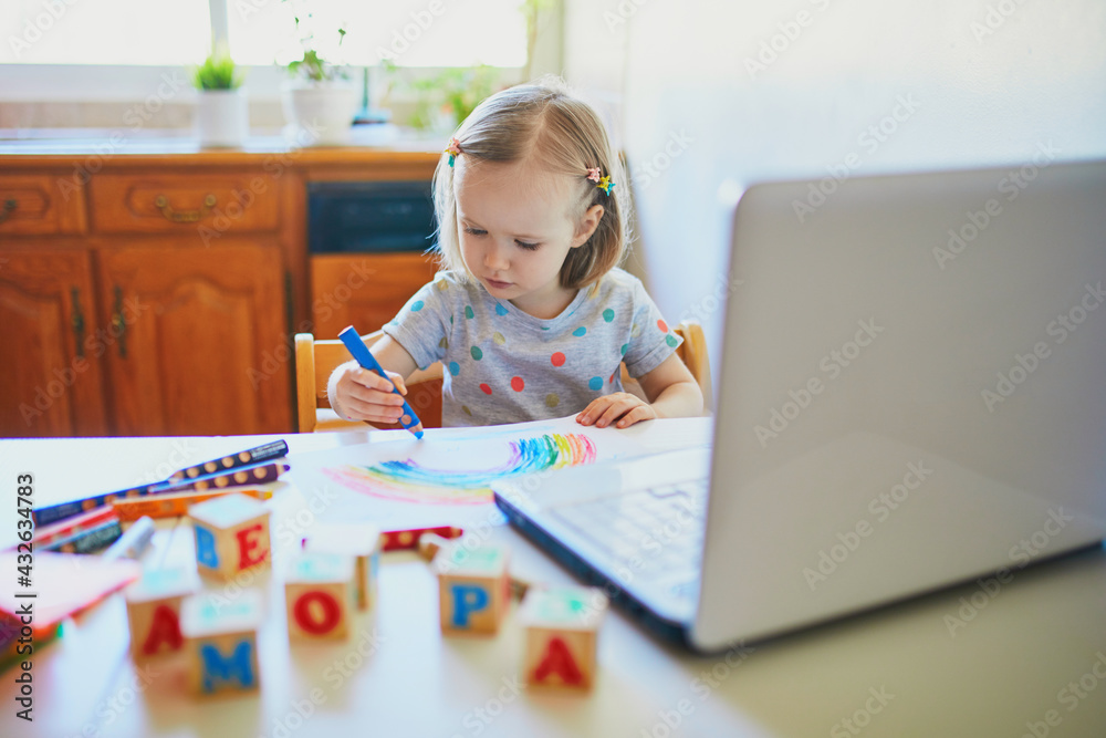 Toddler girl drawing rainbow in front of laptop Toddler girl drawing rainbow in front of laptop
