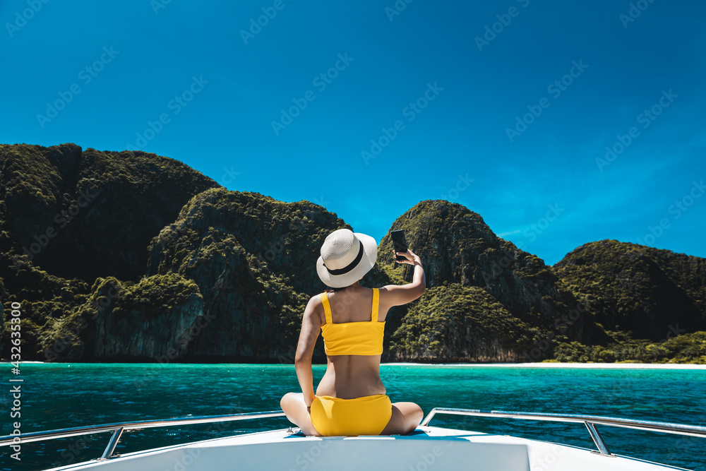 Traveler asian bikini woman with mobile phone travel on boat in Maya Bay Phuket Thailand - obrazy, fototapety, plakaty 