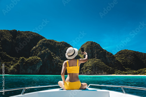 Traveler asian bikini woman with mobile phone travel on boat in Maya Bay Phuket Thailand