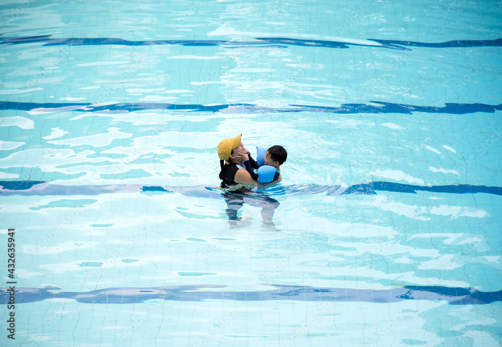 Happy mother and son playing in swimming pool