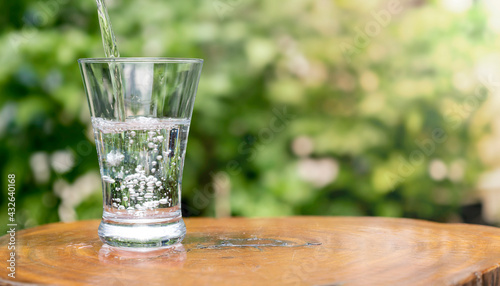 pouring water to glass on table outdoor and nature orange bokeh and sunlight in morning.world water day,save water,