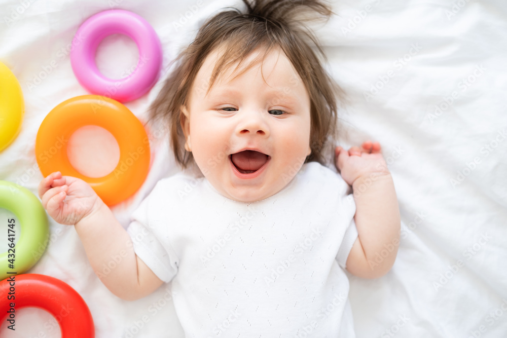 healthy baby boy lying on bed and play with colorful plastic circle toy. healthy baby boy lying on bed and play with colorful plastic circle toy.