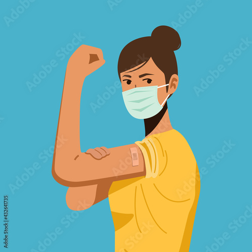 A young woman wearing protective mask showing her arm with bandage after receiving covid-19 vaccine.