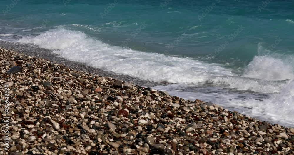 Sea view. Waves run over the rocky pebble beach. Blue color of sea water. Warm summer southern seascape Sea view. Waves run over the rocky pebble beach. Blue color of sea water. Warm summer southern seascape