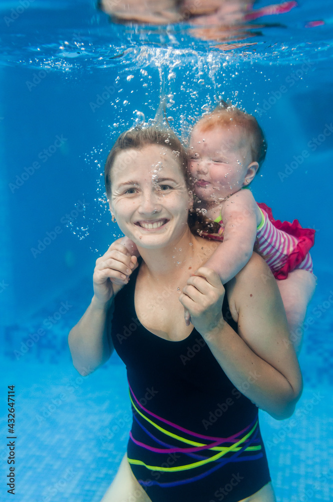 Mother holds baby, daughter learn to swim on swimming lesson, doing