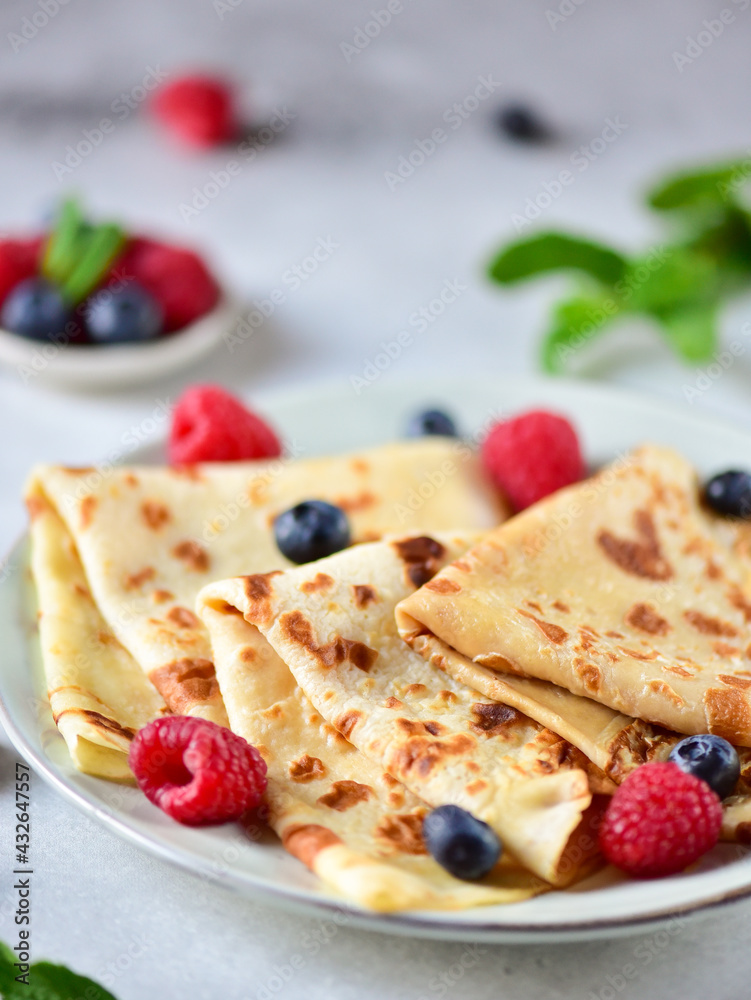 Pancakes with raspberries and blueberries on a plate, on a gray background, side view. Pancakes with raspberries and blueberries on a plate, on a gray background, side view.