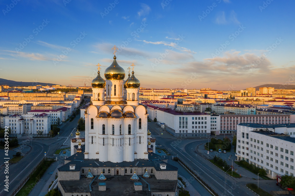 View of the Cathedral, streets and buildings illuminated by the sun at sunrise. Central district of the city of Magadan. Beautiful morning cityscape. Holy Trinity Cathedral. Magadan Region, Russia.