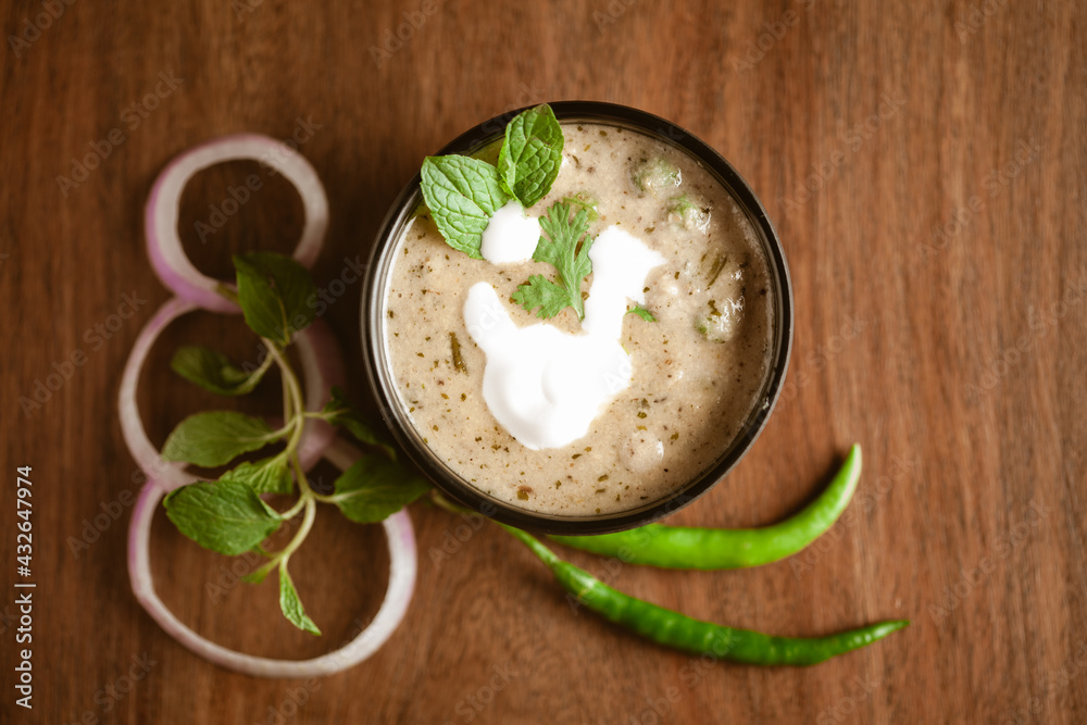Close-up of Methi-Matar-Malai with white curry with fresh green chilies, mint leaves, and onions. A popular, delicious Indian recipe in a black bowl over wooden background. Close-up of Methi-Matar-Malai with white curry with fresh green chilies, mint leaves, and onions. A popular, delicious Indian recipe in a black bowl over wooden background.