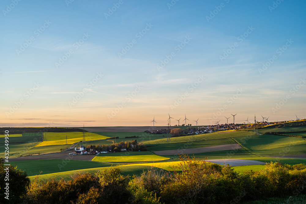 wind turbines over a patch of fields in spring